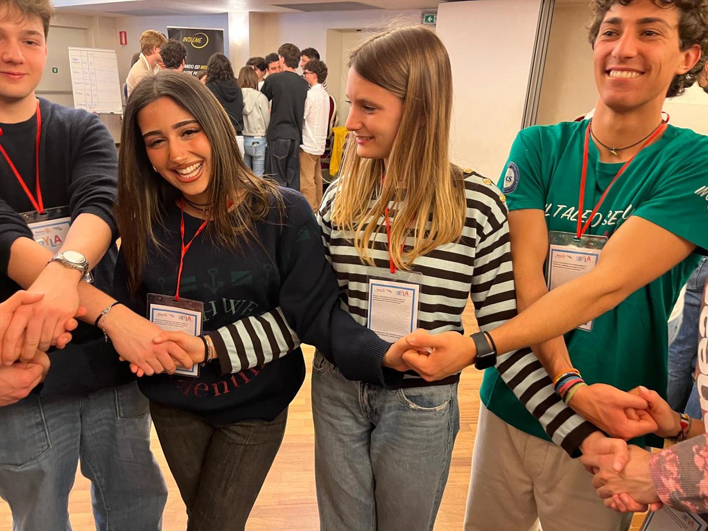 Giovani partecipanti al RYLA che si stringono le mani ridendo